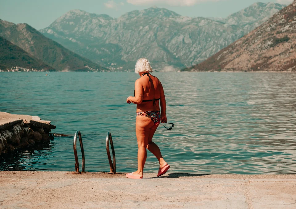 Woman walking towards the water with mountains across the bay